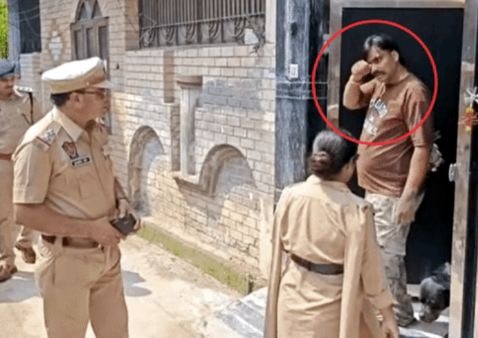 पुलिस के सामने आंखे मलते हुए घर से बाहर निकलता आरोपी।